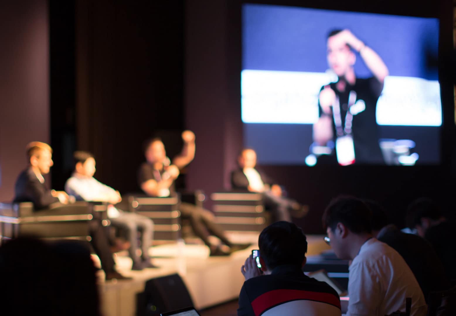 Photo of speakers at a conference on stage