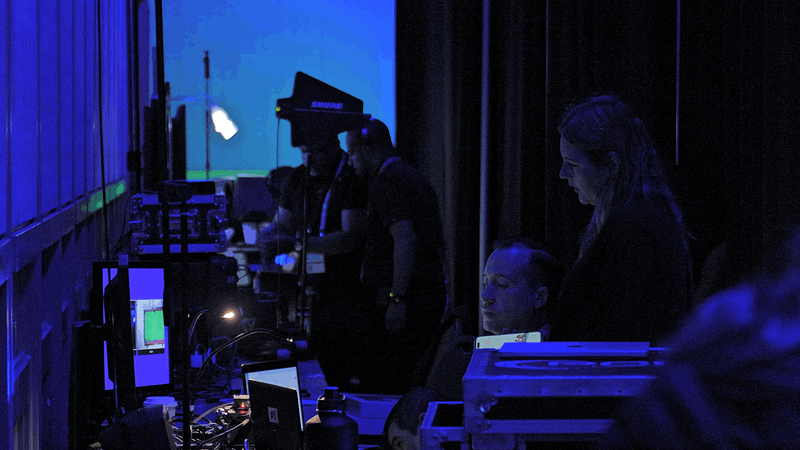 AV crew member and presenter backstage at a conference looking at a laptop screen